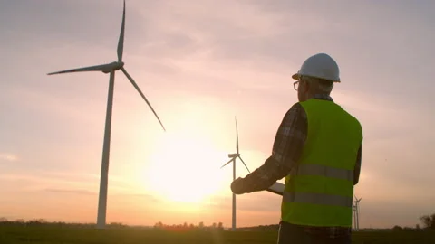 Windmill engineer watching wind turbines in operation on a laptop Stock Footage 197015048