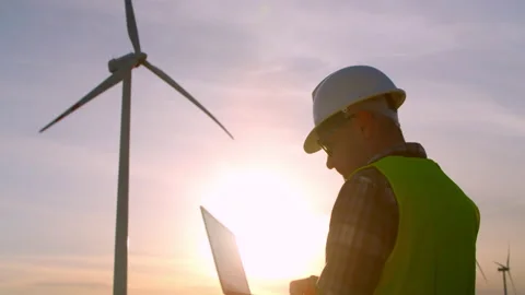 Windmill engineer watching wind turbines in operation on a laptop Stock Footage 198334432