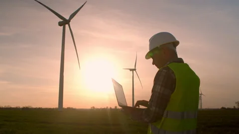 Windmill engineer watching wind turbines in operation on a laptop Stock Footage 198341940