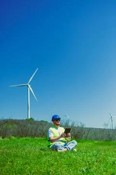 Windmill engineer working on a tablet in a green field with wind turbines u.. Foto stock
