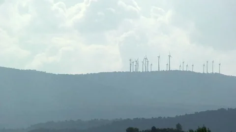Windmill farm on a hill over forests, pan right Stock Footage 50078875
