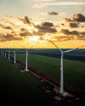 Windmill farm at sunset with dramatic sky. Producing alernative energy Stock Photos