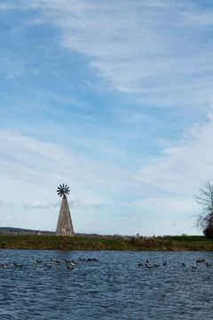 Windmill in front of a lake with blue sky background Stock Photos