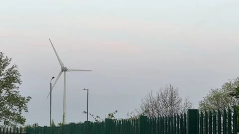 Windmill generating energy behind fence 4K Stock Footage 332607745