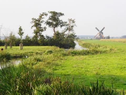 Windmill in green grass fields Stock Photos