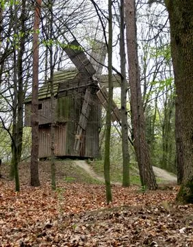 Windmill mill made of wood in a forest park with a screw among the trees Stock Photos
