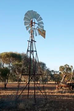 Windmill pumping water from artesian basin in the late afternoon sun Stock Photos