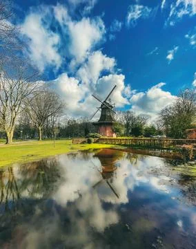 Windmill in the rays of the sun and reflection in the water Stock Photos
