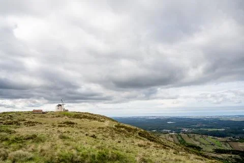 Windmill on ridge beneath storm clouds Stock Photos