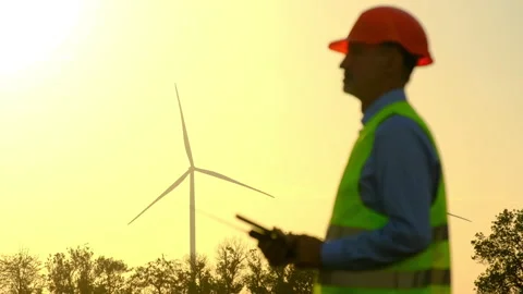 Windmill rotates at sunset engineer looks at substation Vidéo 166810503