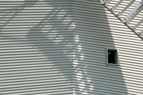 A windmill sail blade casts a shadow across the lined structure Stock Photos