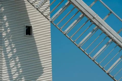 A windmill sail blade casts a shadow across the lined structure Stock Photos