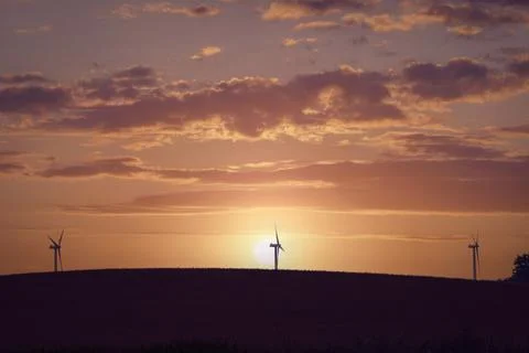 Windmill silhouettes on a hill Stock Photos