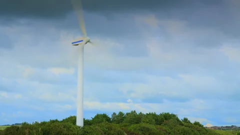 Windmill spinning and clouds racing by with cloud shadows on tree line. Stock Footage 247107650