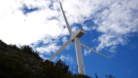 A windmill spinning in the background of blue sky with clouds Video stock 113002689