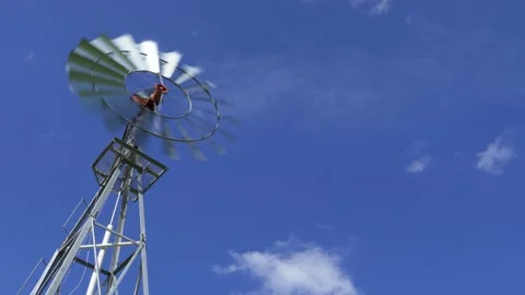 Windmill spinning fast on windy day, low angle against blue sky Stock Footage 130252301