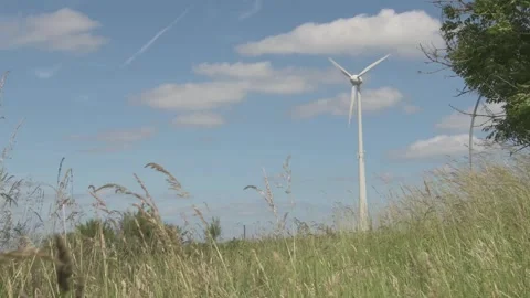 Windmill Spinning Over Grassy Field over Blue Sky Stock Footage 325263197