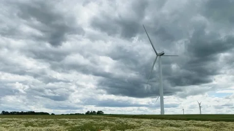 The windmill is spinning slowly, producing environmentally friendly, green en Stock Footage 133173350