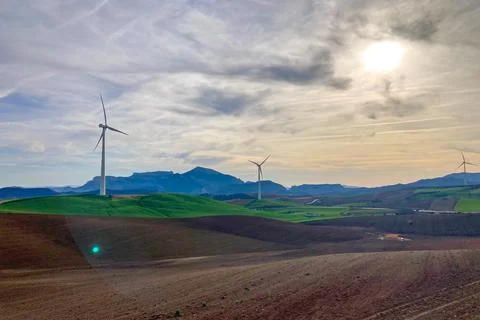 A windmill standing in a field of barley, its blades turning slowly in the wind Stock Photos
