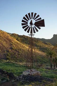 A windmill is standing in a field with a beautiful view of the mountains Stock Photos