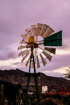 A windmill is standing in a field with a cloudy sky in the background Stock Photos