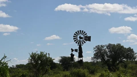 Windmill stands in a field beneath a blue sky Видео 287363695