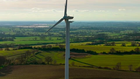 Windmill turbine spinning generating renewable electricity in sunny countryside Stock Footage 325315642