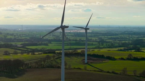 Windmill turbines rotating generating renewable electricity over vibrant green Stock Footage 306015567