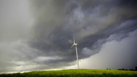 A windmill turning in the wind against storm clouds Stock Footage 136601729