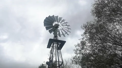 Windmill water pump spinning fast in stormy weather with grey sky Stock Footage 155479453