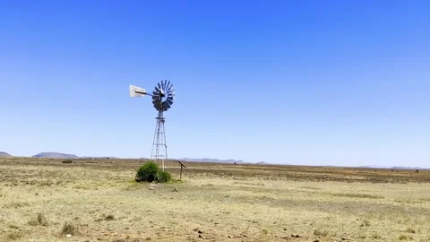 Windmill wind pump borehole in arid landscape Stock Footage 332355172