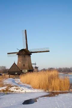 Windmill in winter time with snow, ice and blue sky Stock Photos