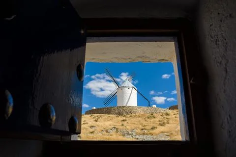 Windmills of Consuegra seen from inside a window of another mill 库存照片