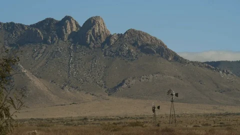 Windmills on a desert ranch with mountains and heat waves Stock Footage 120176085