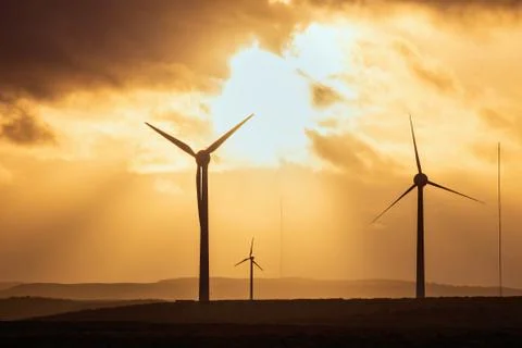 Windmills in a field at sunset on the background of dramatic sky Stock Photos
