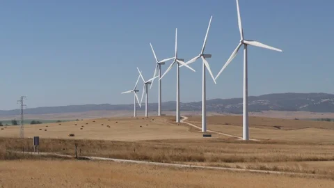 Windmills generating electricity on an open field Stock Footage 107608622