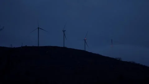 Windmills on a hill at night, with mist rolling towards them. Stock Footage 325957572