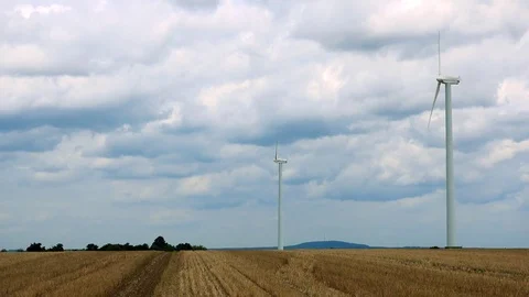 Windmills in the middle of a field, trees, a hill and the cloudy sky in the Stock-Footage 73957009