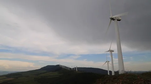 Windmills on mountaintop spinning on a cloudy day Stock Footage 123979663