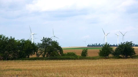 Windmills with rotating blades in the middle of a field, the blue cloudy sky in 動画素材 73956985