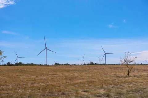 Windmills spin in the field. Stock Photos