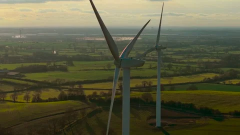 Windmills spinning over vibrant fields generating renewable electricity. Wind Stock Footage 325315638