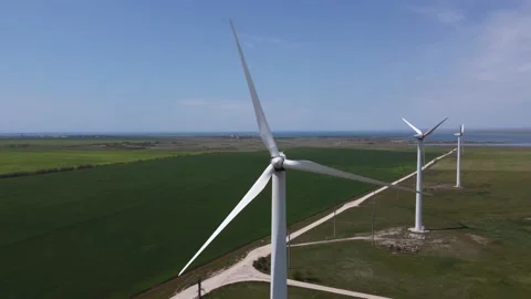 Windmills stand in the middle of fields, the sea can be seen in the background Stock Footage 154764503