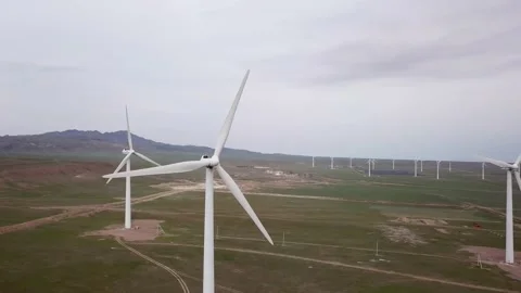 Windmills stand in the middle of green fields. Video stock 152976678