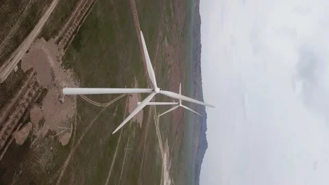Windmills stand in the middle of green fields. Video stock 152976779