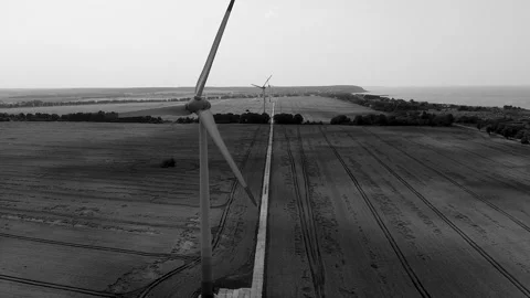 Windmills stand in a row in a field, black and white video from a drone Stock Footage 180043833