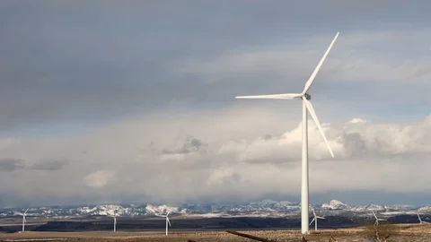 Windmills turning with cloudy sky and snowy mountains Stock Footage 106585649