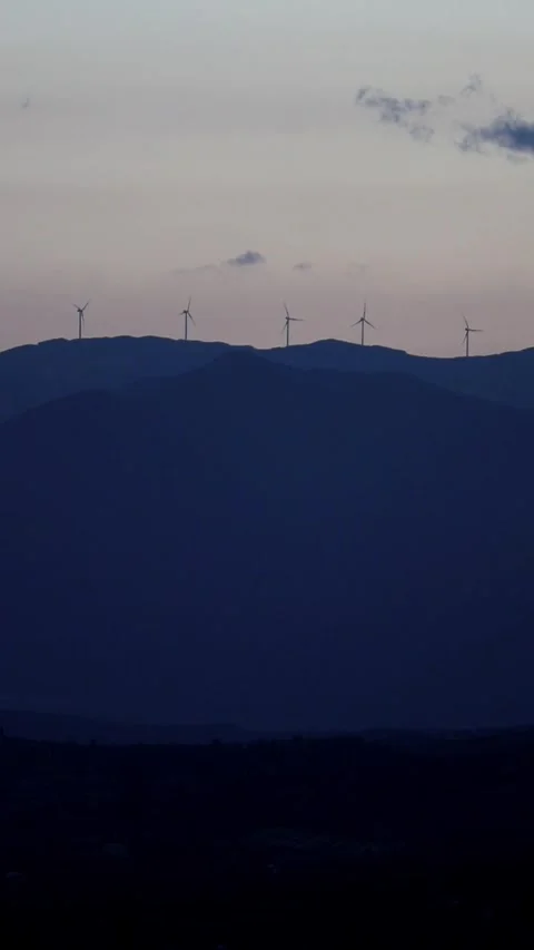 Windmills turning on distant hills at sunset golden hour Stock Footage 277065724