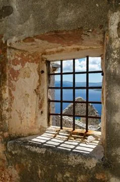 Window on abandoned ruins with rusty bars overlooking Adriatic sea Stock-Fotos