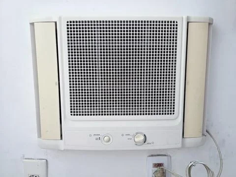 Window air conditioner unit on a white wall with visible power cord Photos